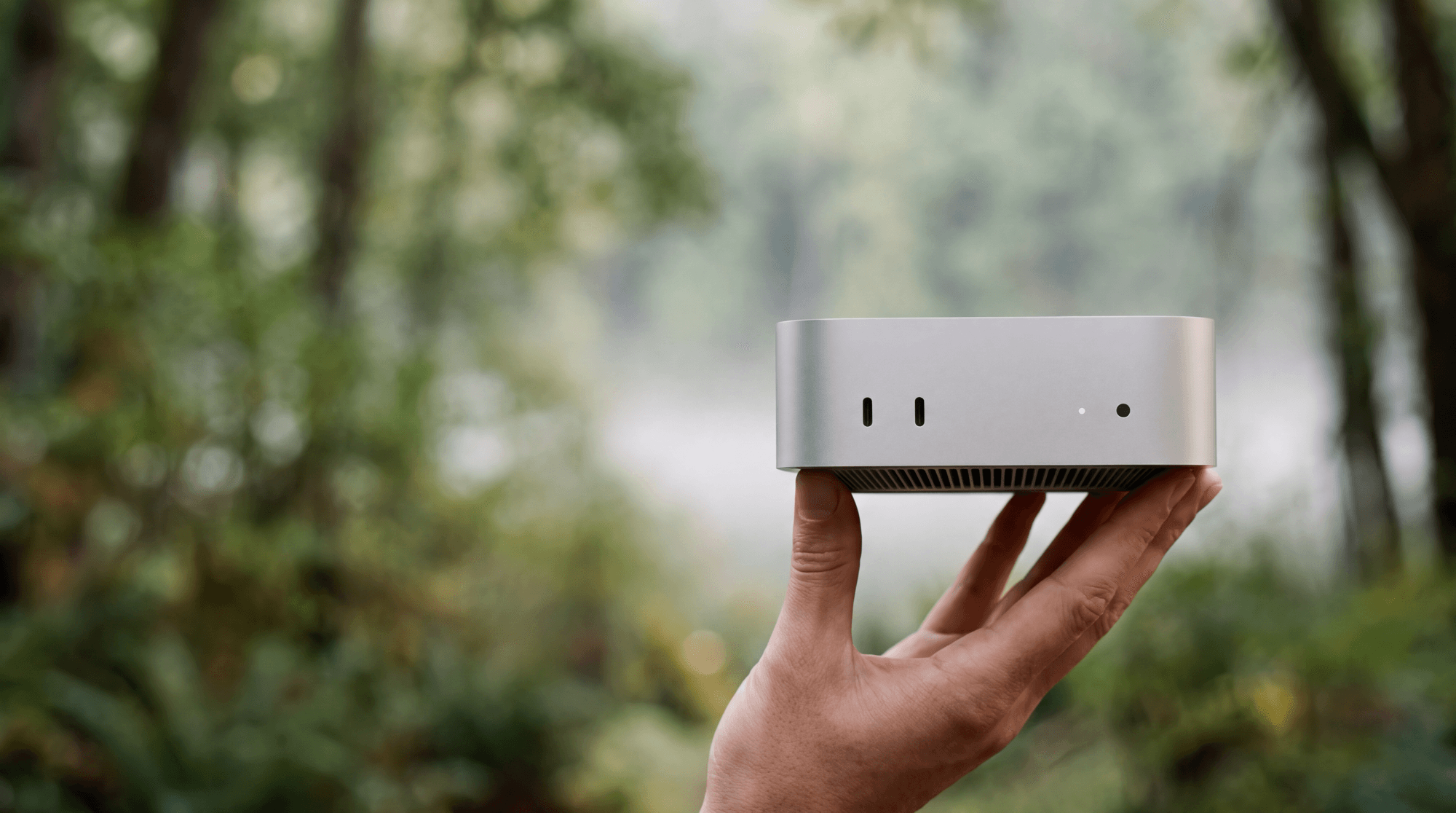 A small computer held up in one hand in a misty forest
